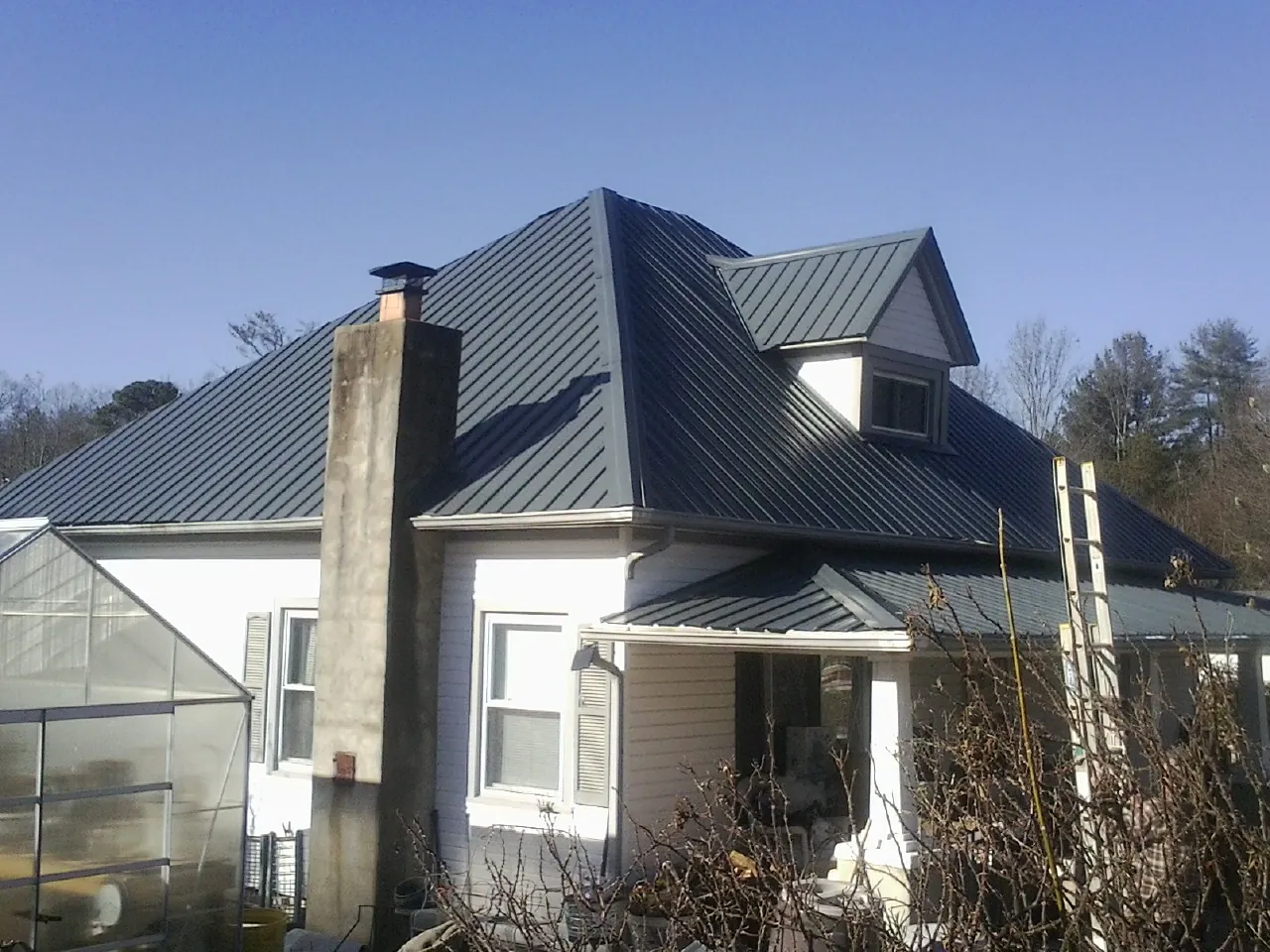 Dark blue standing seam metal roof on a white farmhouse with dormer — Slate & Tile Roof Repair by Roofing Brothers in Eliot