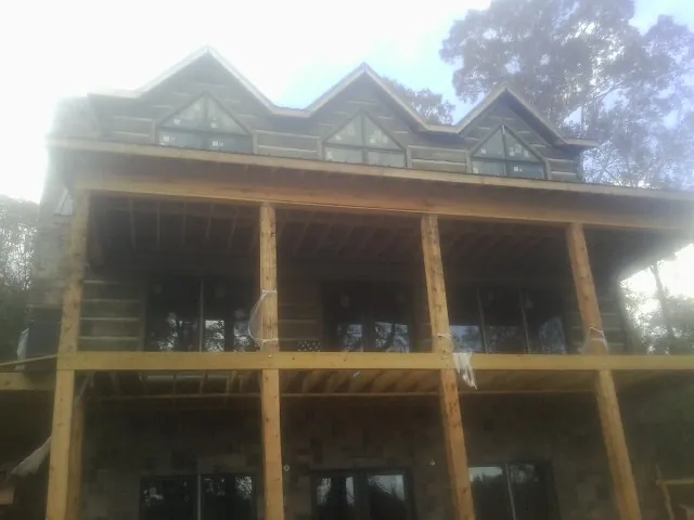 Dormers and porch framing on a large log home under construction — Roof Coating work by our crew in Eliot