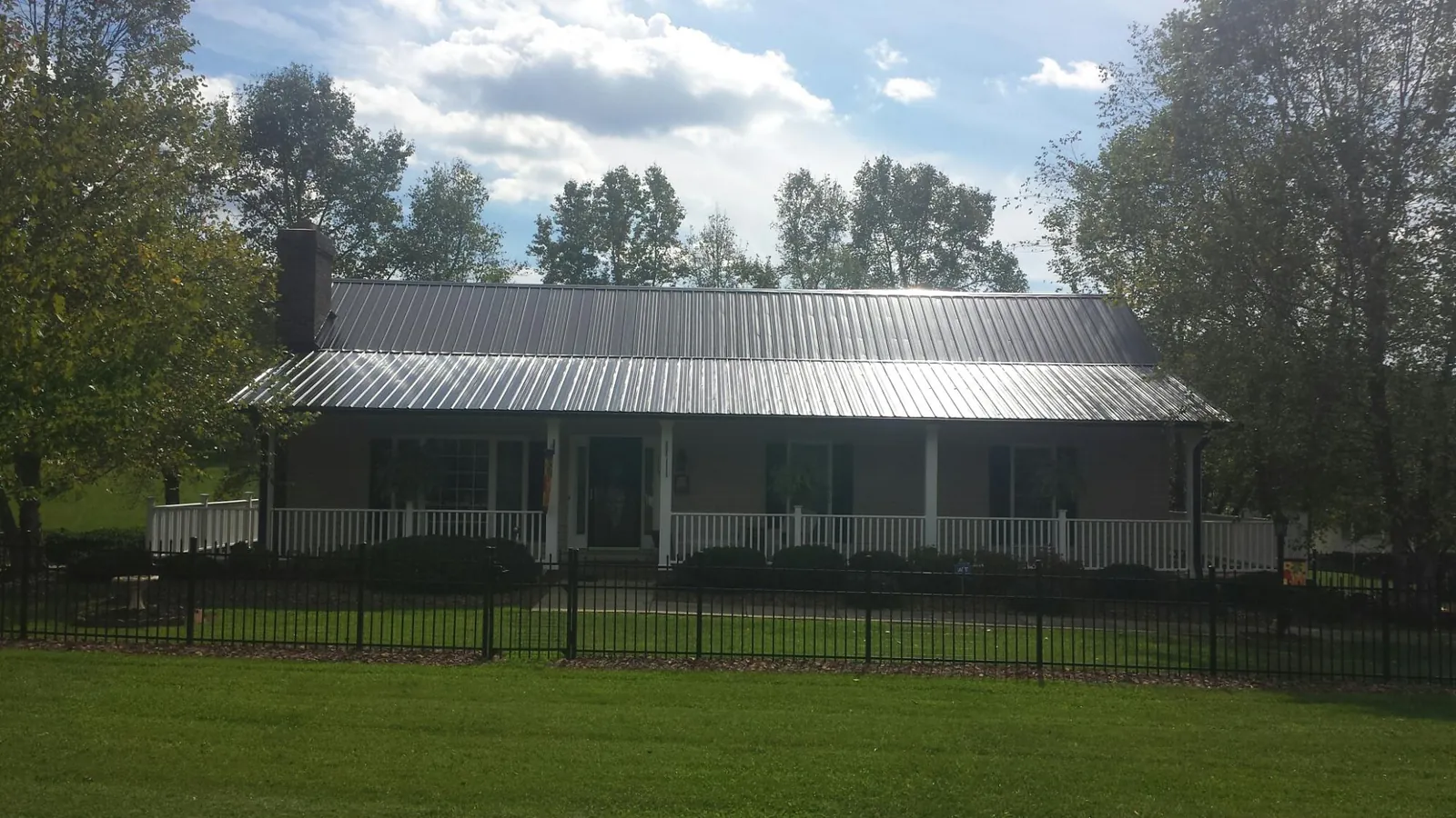 Gray metal roof on a brick ranch with a full width front porch — Gutter Guard Installation work by our crew in Eliot