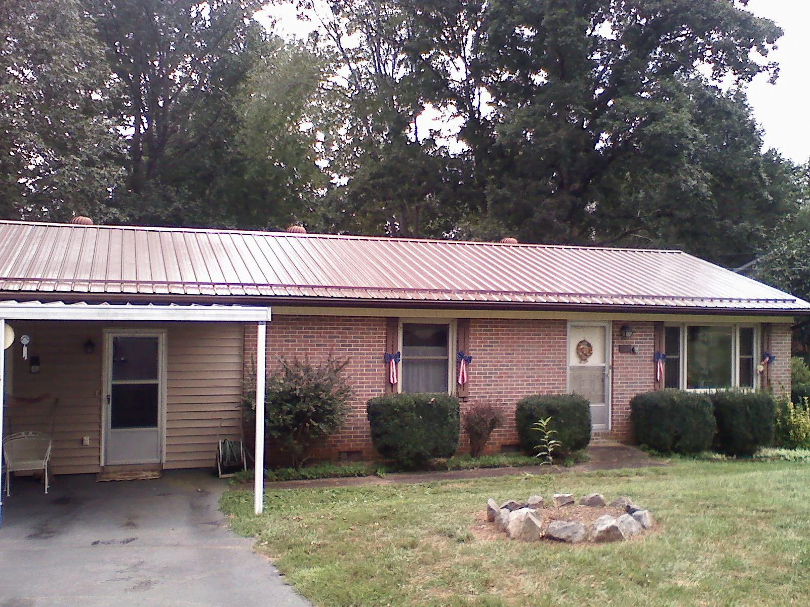 Bronze metal roof and carport on a brick ranch home — Roof Repair work by our crew in Eliot